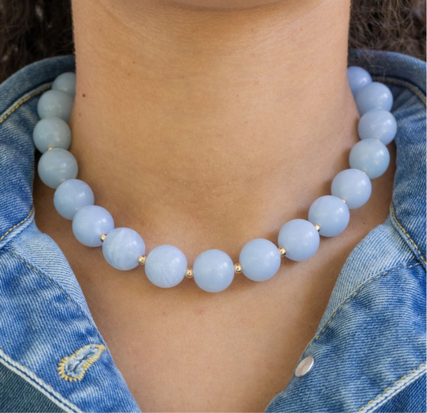 Light blue chunky beaded necklace worn by a person with denim clothing.