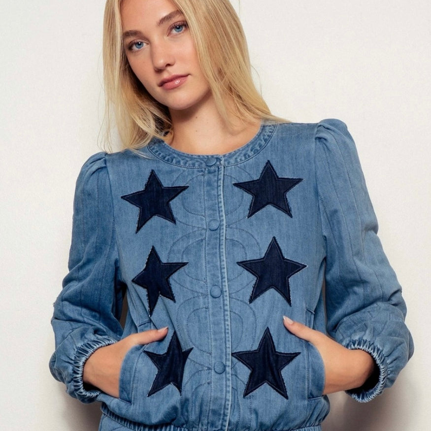 Woman wearing a denim jacket with star patterns on a plain background