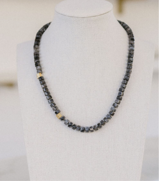 Picture of a gray beaded necklace with two gold accent beads.