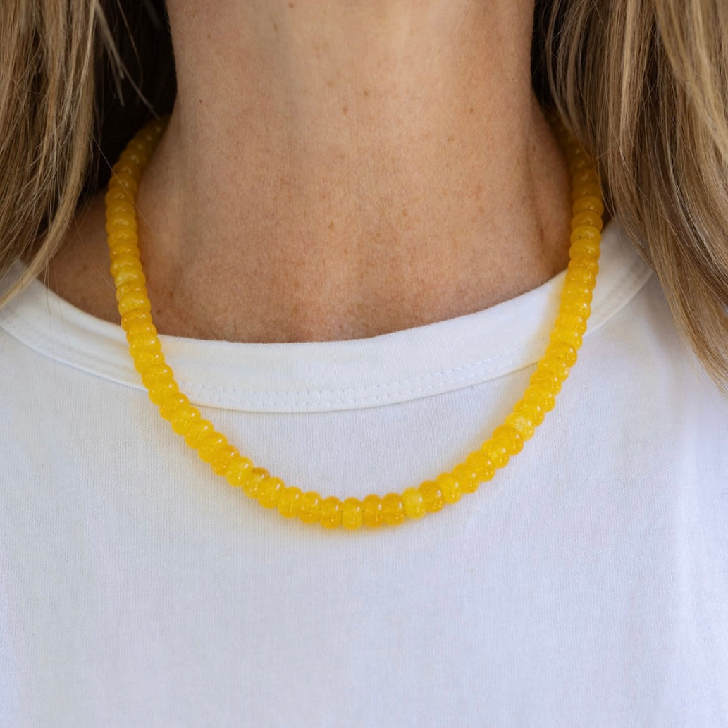 Yellow beaded necklace worn by a person on a white background