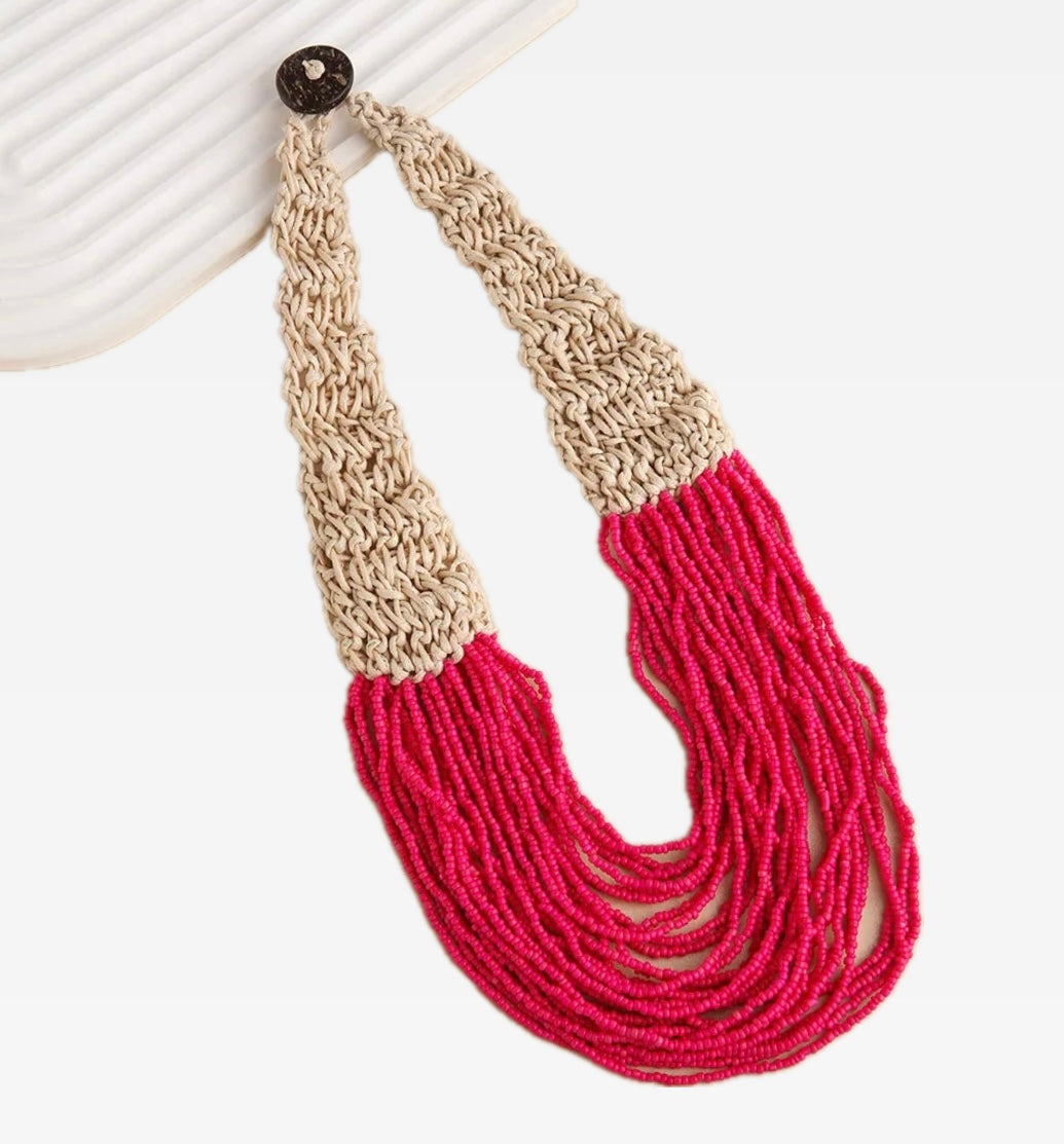 Necklace with beige and red bead strand sections on a white background