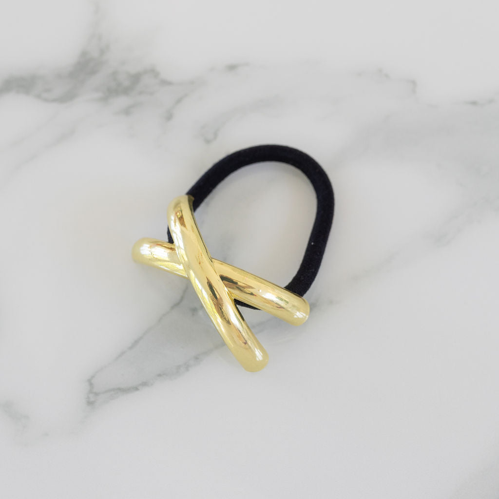 Gold hair tie with black rubber band on a marble background