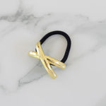 Gold hair tie with black rubber band on a marble background
