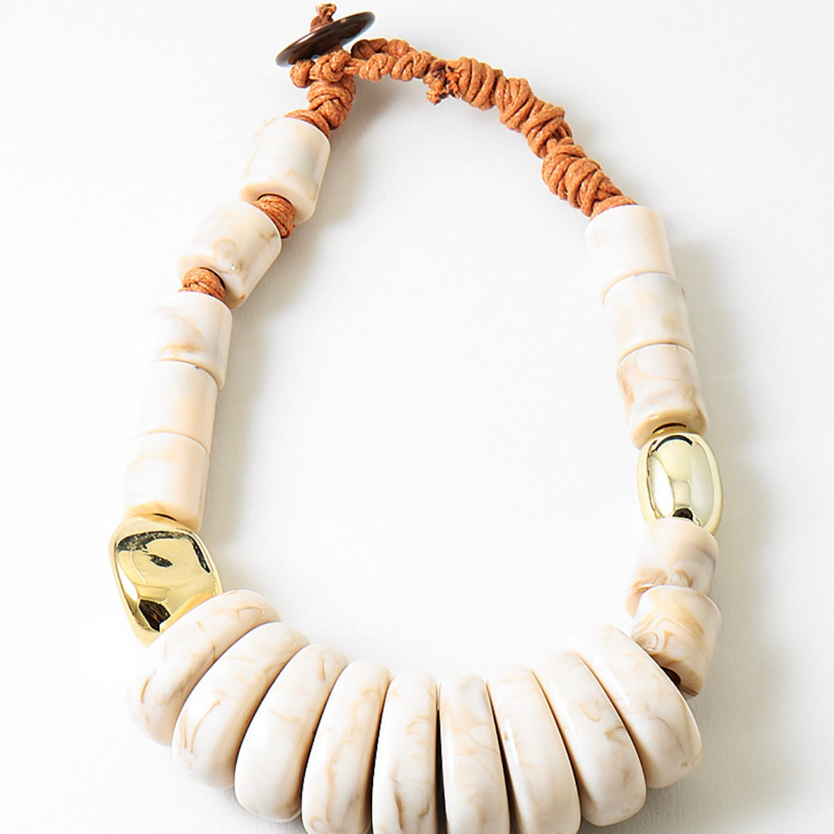 Large statement necklace with white beads and gold accents on a white background