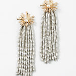 Gold starburst earrings with a pearl center and 8 white bead strands dangling from them.