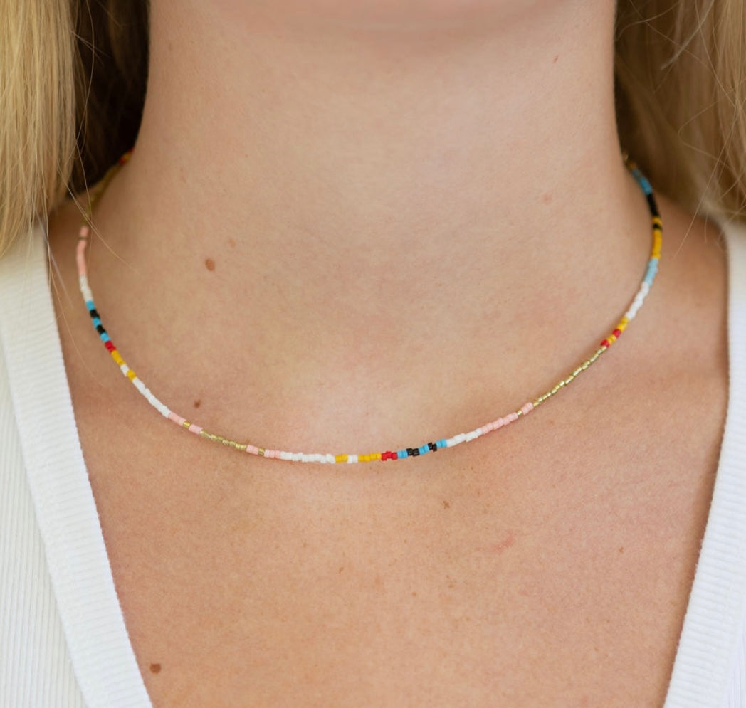 Multicolored beaded necklace on a person wearing a white top