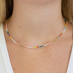 Multicolored beaded necklace on a person wearing a white top