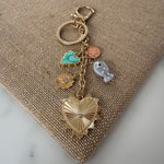 Keychain with heart-shaped charm and various other charms on a textured surface