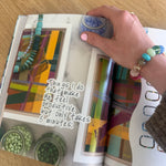 Person holding a colorful book with abstract designs on a wooden surface