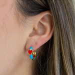 Close-up of an ear wearing a colorful blue hoop earring with a heart design.