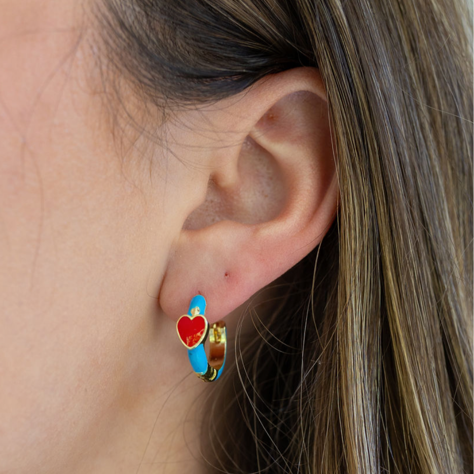 Close-up of an ear wearing a colorful blue hoop earring with a heart design.