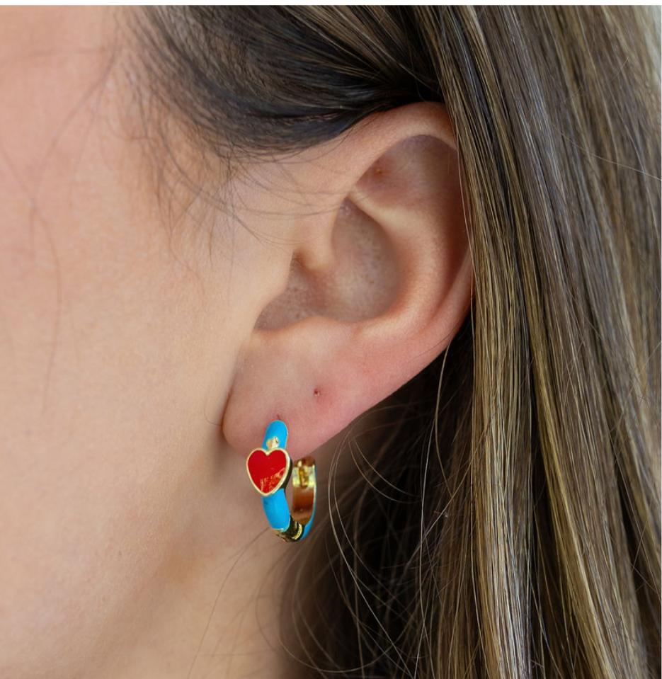 Close-up of an ear wearing a colorful blue hoop earring with a heart design.