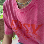 Picture of a woman wearing a pink Tshirt and two dainty bead necklaces. One necklace is yellow and white, one in dark and light blues.