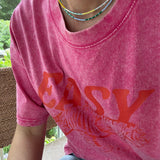 Picture of a woman wearing a pink Tshirt and two dainty bead necklaces. One necklace is yellow and white, one in dark and light blues.