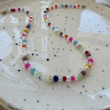 Colorful and clear beaded necklace on a speckled ceramic plate