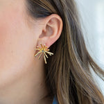 Picture of a woman wearing a gold starburst stud.