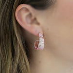 Close-up of an ear wearing a pink earring with floral design