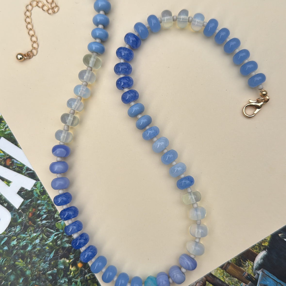 Beaded necklace with blue and clear stones on a beige background