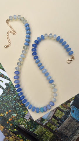 Beaded necklace with blue and clear stones on a beige background