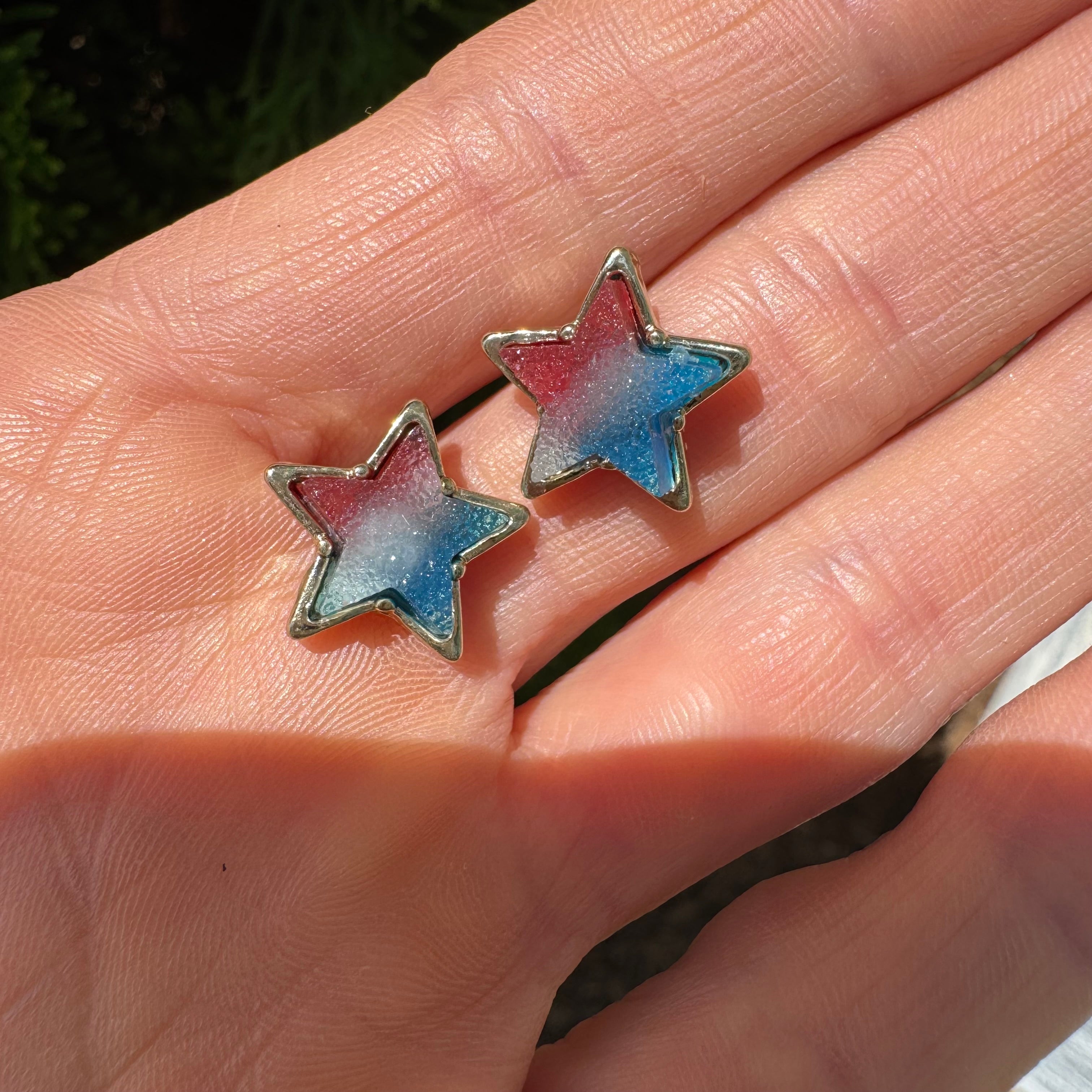 Picture of a hand holding red, white and blue druzy star studs.