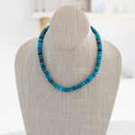 A semi-precious stone necklace with shades of blue beads displayed on a mannequin bust.