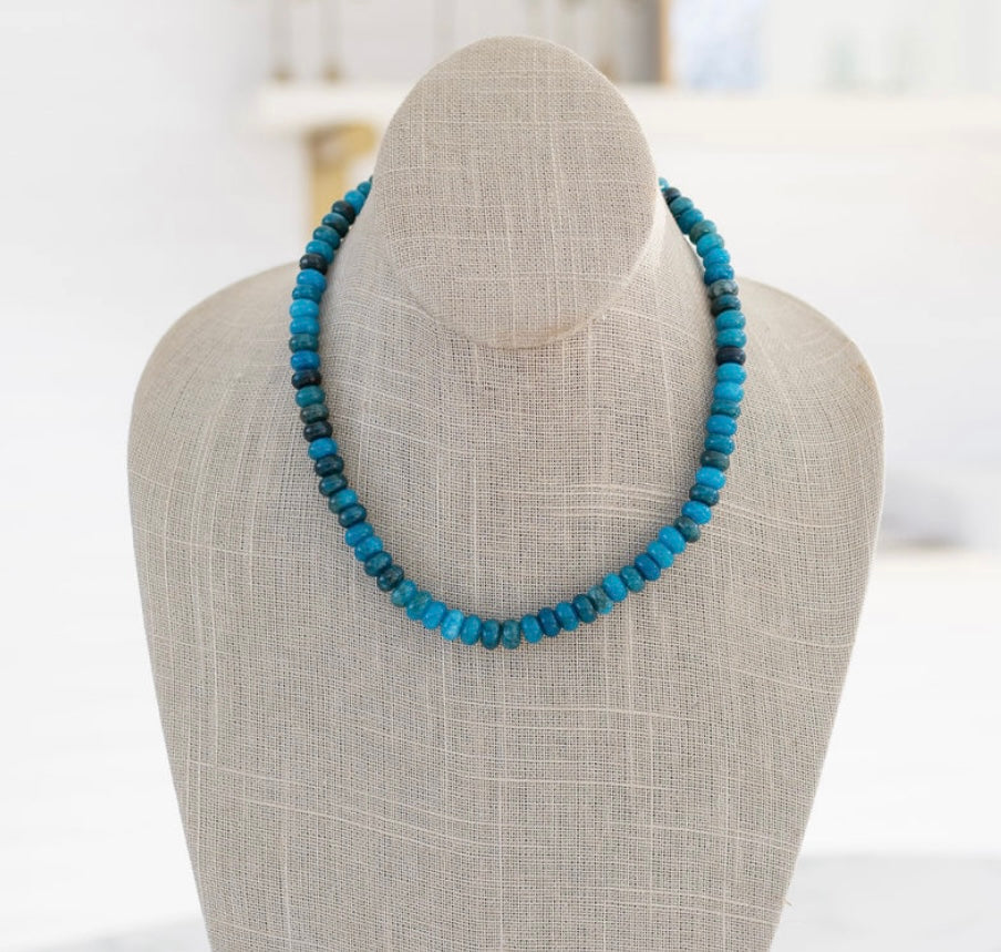 A semi-precious stone necklace with shades of blue beads displayed on a mannequin bust.