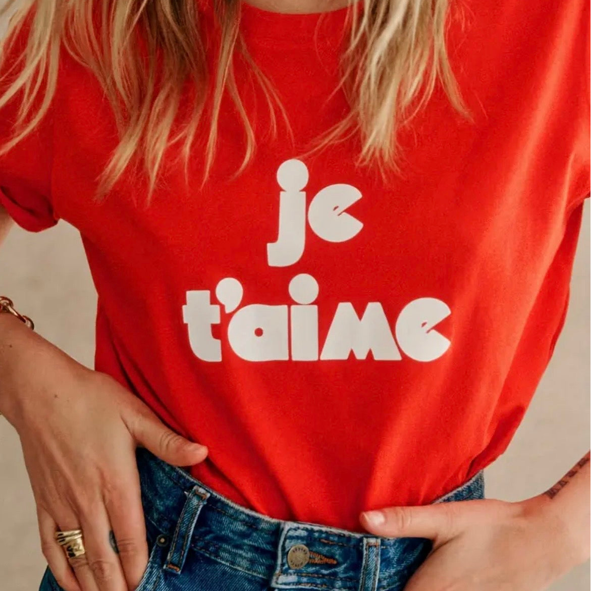 Red t-shirt with 'je t'aime' text worn by a person, with a neutral background
