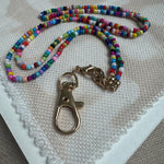 Picture of a multicolored beaded lanyard with a large gold clasp.