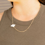 Gold chain necklace with a small pendant worn by a person in a green sleeveless top.