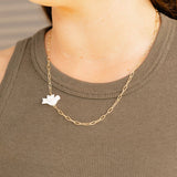 Gold chain necklace with a small pendant worn by a person in a green sleeveless top.