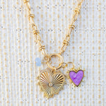 Picture of gold toggle chain that has a blue bead charm, purple heart charm and large gold heart pendant with diamond at the center.