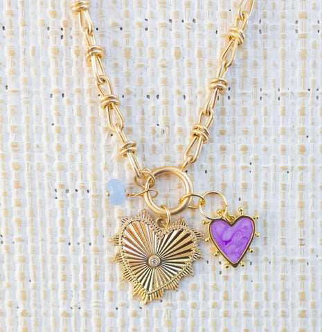 Picture of gold toggle chain that has a blue bead charm, purple heart charm and large gold heart pendant with diamond at the center.