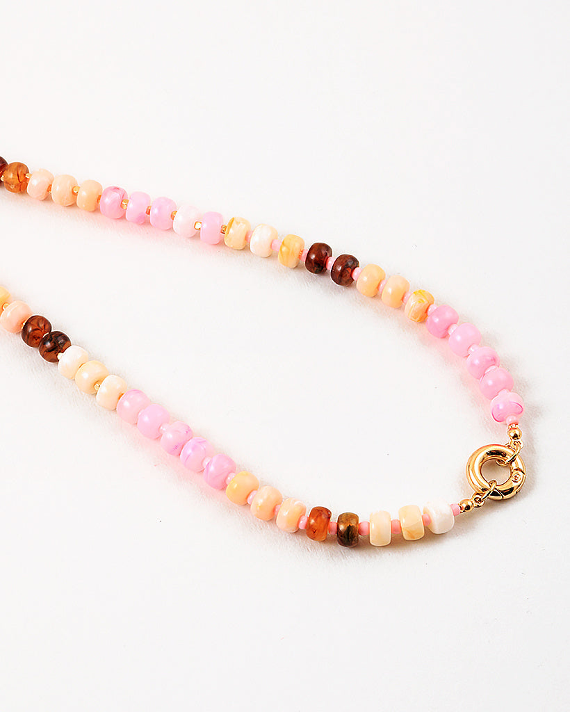 Necklace with multicolored pink and peach beads and a gold clasp on a white background