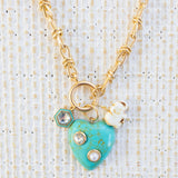 Picture of gold toggle chain with a large turquoise heart with diamond and pearl inlays. Necklace has a white elephant charm and a diamond with turquoise border charm.