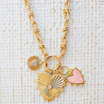 Picture of gold toggle chain with a pink heart charm, a textured gold charm with diamond heart and a large gold heart pendant with a diamond in the center.