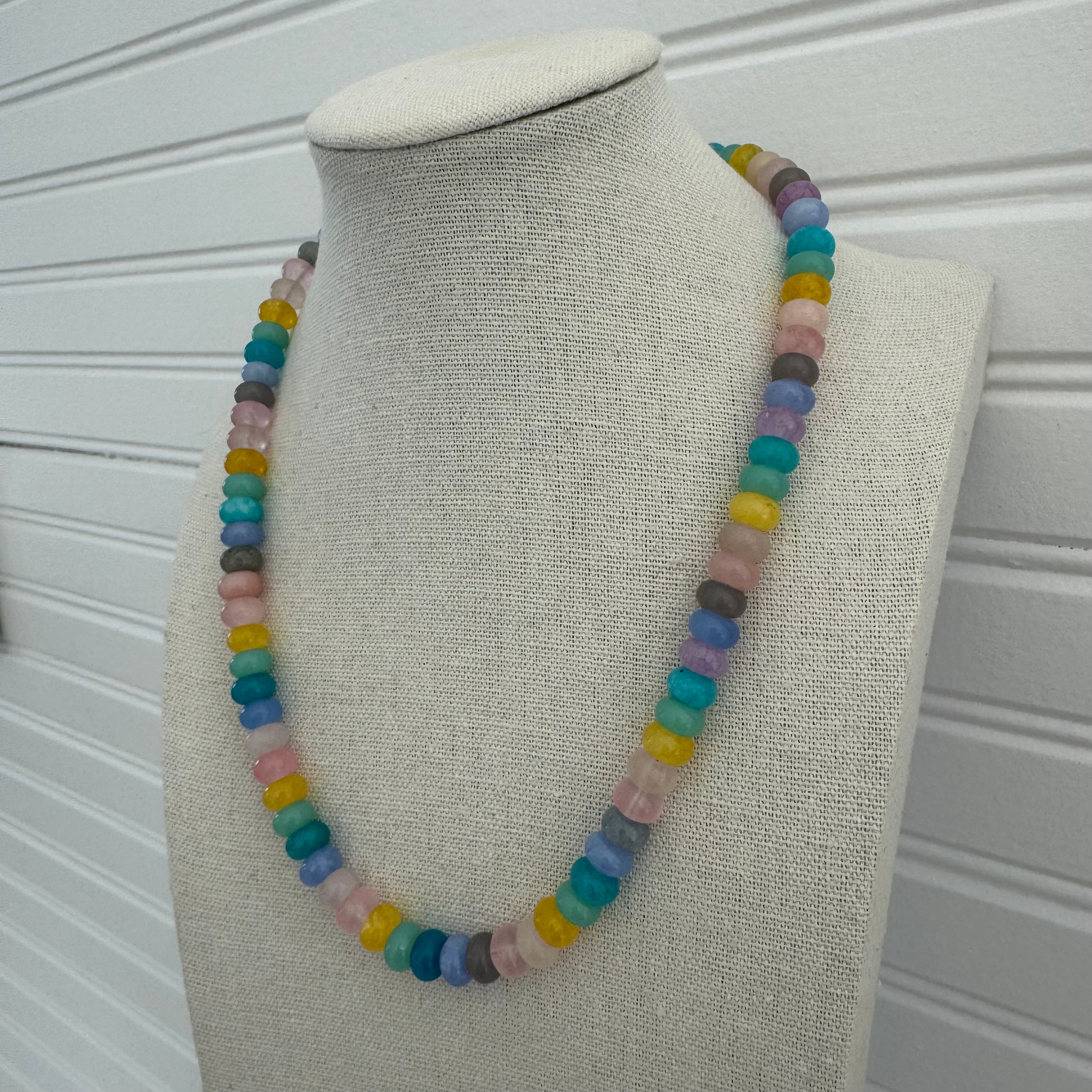 Picture of a necklace made of purple, blue, white, yellow and pink beads.
