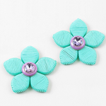 Two turquoise flower-shaped earrings with purple centers on a white background