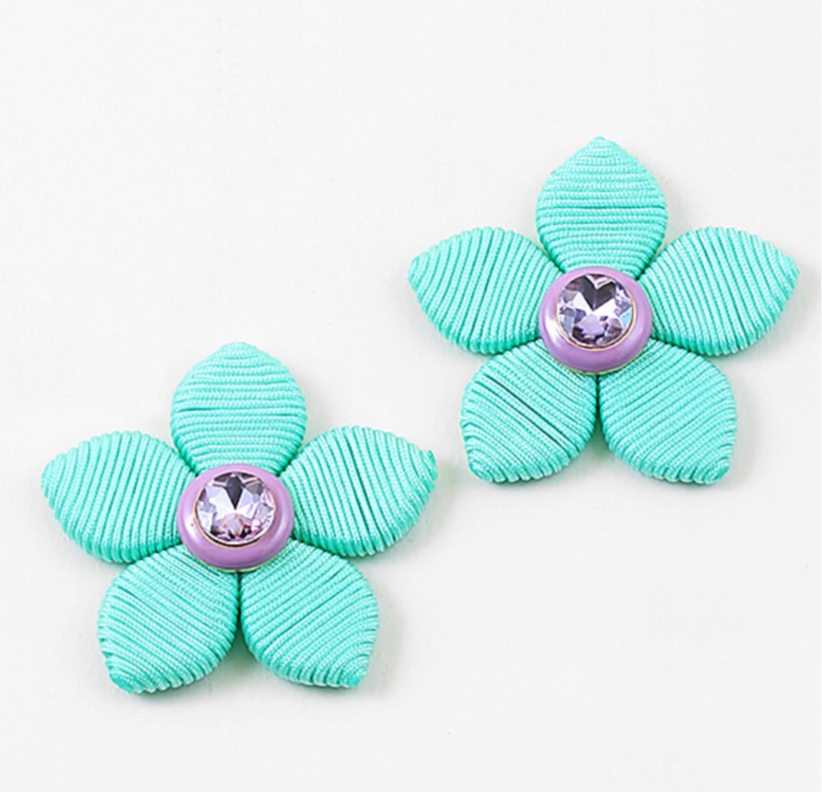Two turquoise flower-shaped earrings with purple centers on a white background