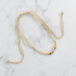 Sliding braided corded necklace of tan, orange and blue with gold beads and an evil eye pendant.