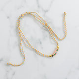 Sliding braided corded necklace of tan, orange and blue with gold beads and an evil eye pendant.