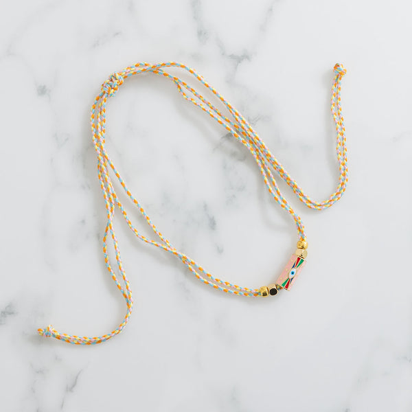 Sliding braided corded necklace of tan, orange and blue with gold beads and an evil eye pendant.