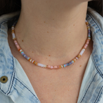 Woman wearing rainbow colored beaded short necklace around her neck