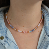 Woman wearing rainbow colored beaded short necklace around her neck