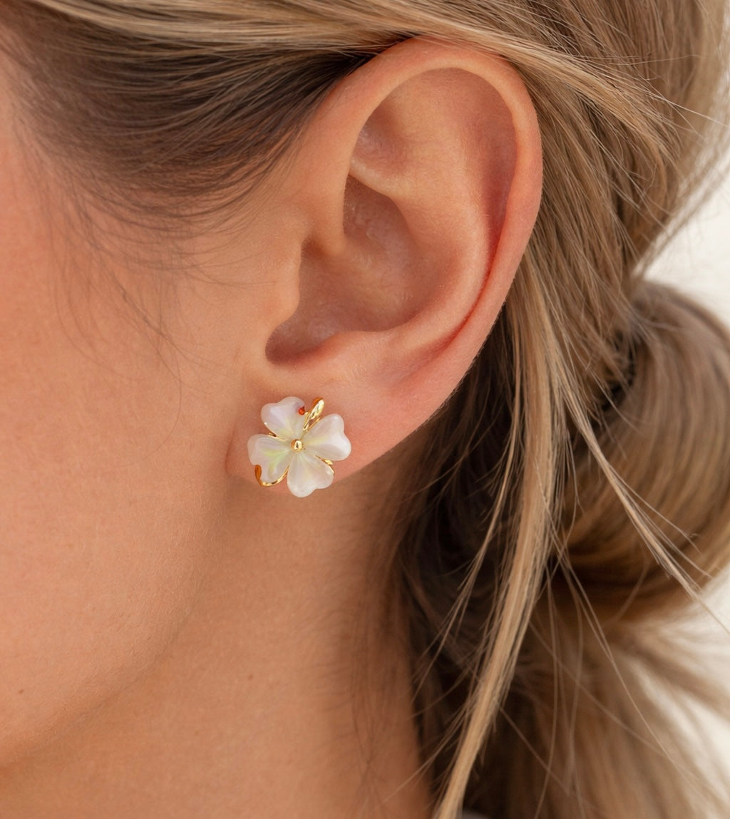 Close-up of an ear wearing a floral earring with gold accents.