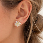 Close-up of an ear wearing a floral earring with gold accents.