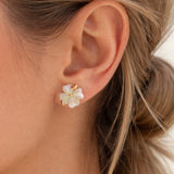 Close-up of an ear wearing a floral earring with gold accents.