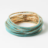 Set of gold beaded bracelets with tiny turquoise stones on a white background