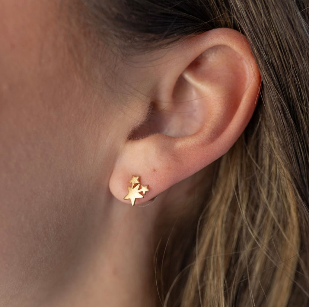 Three gold star stud on an ear