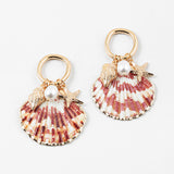 Set of half shell earrings with gold tipped edges. Earrings hang from small gold hoops with three small pendants dangling from them. One is a small golden conch, a golden starfish and a small fresh water pearl.
