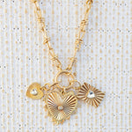 Picture of gold toggle chain with three pendants attached. One large gold heart with a diamond in the center, one small gold heart with a heart diamond in the center and one textured rectangle with a diamond heart in the center.